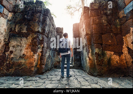 L'uomo backpacker passeggiata all interno di Prasat Muang cantare sono le antiche rovine del tempio Khmer nel parco storico Foto Stock