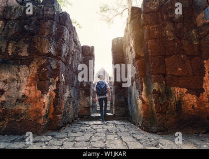 L'uomo backpacker passeggiata all interno di Prasat Muang cantare sono le antiche rovine del tempio Khmer nel parco storico Foto Stock