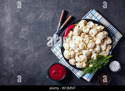 Deliziosi gnocchi caldi serviti su una piastra nera con aneto e salsa di pomodoro, vista da sopra, flatlay, spazio di copia Foto Stock