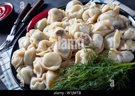 Close-up di caldo in casa gnocchi con carne di manzo macinata ripieno servito su una piastra nera con aneto e salsa di pomodoro con vista orizzontale dal di sopra Foto Stock