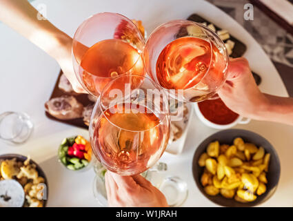 Mani tenendo i bicchieri di vino rosato sopra la tavola con il cibo. Summer Party concept Foto Stock