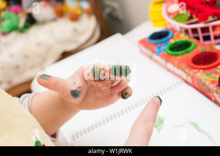 Сolorful kid's dito nella vernice. Bambino i quadratini colorati con vernice, il bambino a tavola è divertente per disegnare e giocare con vernici Foto Stock