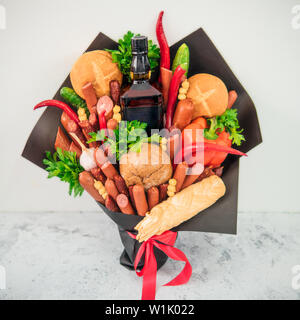 Carne e cheese bouquet per l'uomo. Mangiare bouquet su sfondo grigio. Salsicce, verdura, formaggio, pane e forte la bottiglia di alcool nel mazzo. Regalo insolito per uomo brutale. Foto Stock