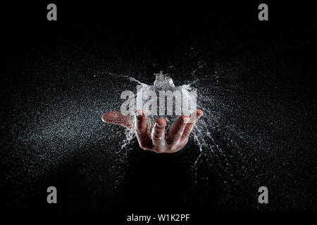 Esplosione di un palloncino pieno di acqua trattenuta su un lato, sfondo nero studio shot. Hi Speed per la fotografia Foto Stock
