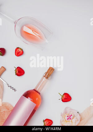 Creative piatto estivo lay con vino rosato, gustose fragole e belle le peonie sullo sfondo bianco Foto Stock