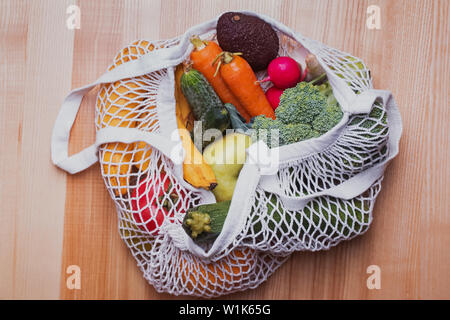 Diversi ortaggi e frutti dal mercato agricolo riutilizzabili in eco-friendly borsa sul tavolo in legno Foto Stock