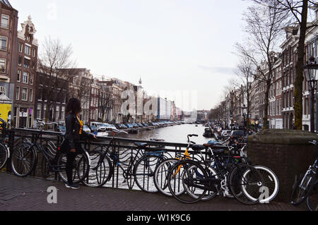 Una giovane donna è guardando Canal a Amsterdam, Paesi Bassi Foto Stock