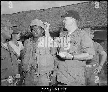 Il Vietnam. John Wayne segni privato di prima classe Wofford Fonsell il casco durante la sua visita al 3° Battaglione, 7 Marines, a Chu Lai.. Foto Stock