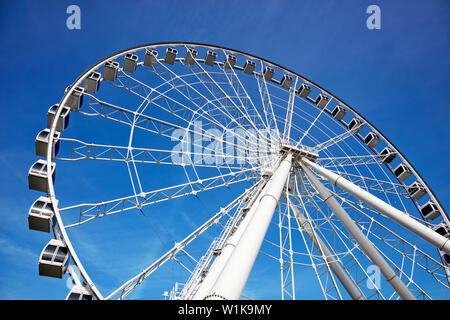 Ruota panoramica sul cielo azzurro sfondo nel parco di divertimenti. Imponente vista da sotto Foto Stock