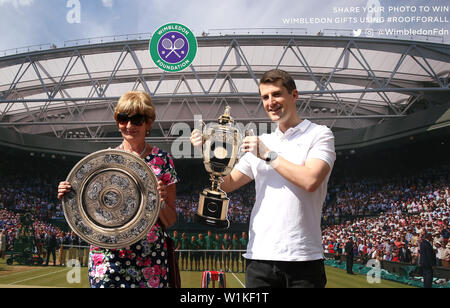 Gli spettatori posano con tagli di cartone dei trofei all'inizio del terzo giorno del Wimbledon Championships presso l'All England Lawn Tennis and Croquet Club di Londra. Foto Stock