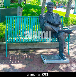 Scultura in bronzo il giorno dopo con un uomo seduto su una panchina leggendo un giornale Montgomery County Courthouse storico giardino Clarksville USA. Foto Stock