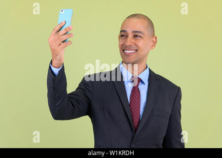 Felice bald multi etnico imprenditore video chiamate con il telefono Foto Stock