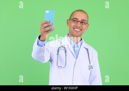 Felice bald multi etnico medico uomo video chiamate con il telefono Foto Stock