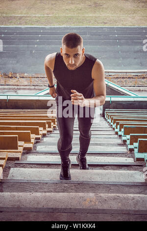 Uomo caucasico treni in esecuzione su per le scale. La via e il campo runner in uniforme di sport outdoor training. atleta, vista dall'alto. passo esercizi. verticale. Foto Stock