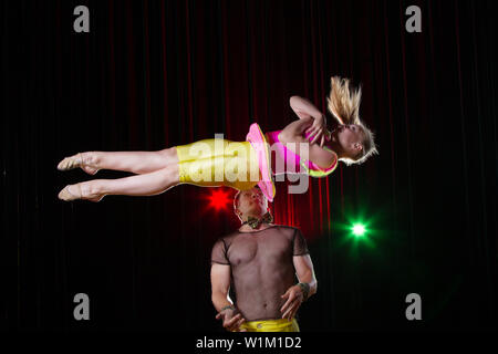 Artisti circensi eseguire acrobazie. Il ginnasta guy genera una ragazza. Circus stunt Foto Stock