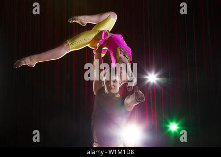 Artisti circensi eseguire acrobazie. Il ginnasta guy detiene una ragazza sul suo braccio. Circus stunt Foto Stock