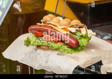 Descrizione: deliziosi waffle bolla con uova fritte e le fette di salsiccia sulla tavola di legno, primo piano Foto Stock