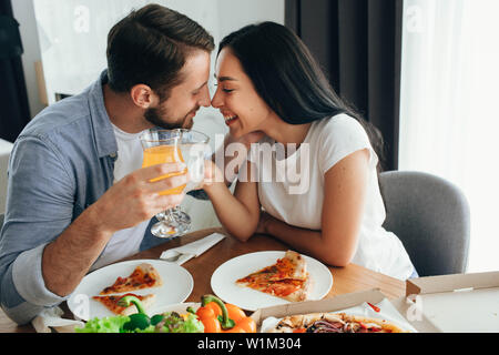Felice coppia baciare e cenare con la pizza a casa. La sua una buona volta la spesa home Foto Stock