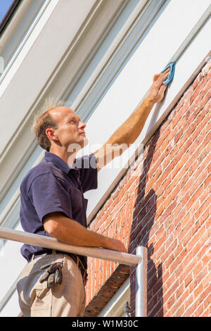 Pittore olandese lavora su impalcature di pulizia di stampaggio del tetto con un panno Foto Stock