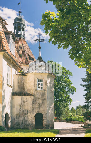 Un antico castello con torri e weathercocks in un parco verde della città di Jaunpils in Lettonia in una giornata di sole Foto Stock