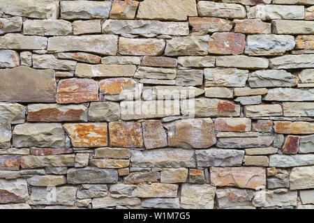 Un frammento di muratura in pietra da grigio e pietra rossastra nella luce naturale. Tessitura della pietra. La parete di un edificio tipico di montagna auls di Caucas Foto Stock