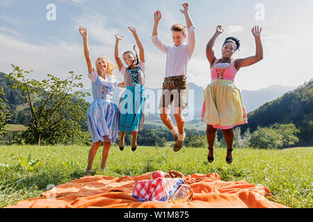 Amici di adolescenti salti di gioia durante il picnic, Baviera, Germania Foto Stock