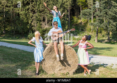 Teenage amici a suonare e cantare la musica durante il picnic, Baviera, Germania Foto Stock