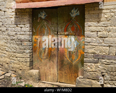 La porta della vecchia casa degli alpinisti nel Daghestan aul Harbuk. Vintage porta di una vecchia casa in una giornata di sole con fiori e uccelli. Artigianato Foto Stock