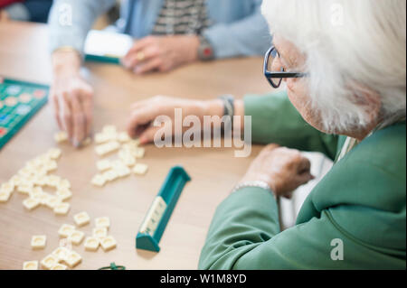 Senior abitanti la riproduzione di gioco di bordo in casa di riposo Foto Stock