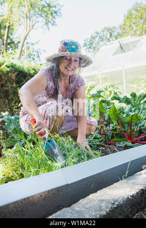 Donna felice di lavorare con una pala in un orto, Altötting in Baviera, Germania Foto Stock