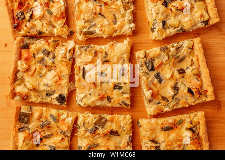 Un ingrandimento della foto a casa le zucchine e formaggio di capra con torta di salvia, girato dalla parte superiore su di un tagliere di legno Foto Stock