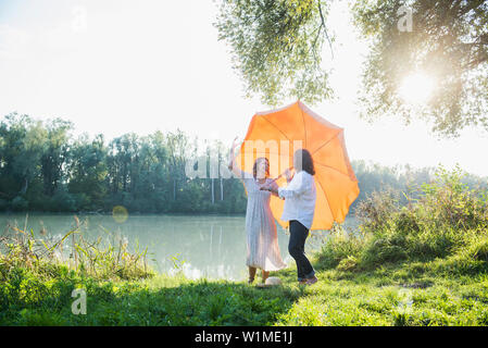 Giovane divertirsi sotto l'ombrellone a riverbank, Baviera, Germania Foto Stock