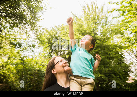 Padre con figlio agendo come supereroe in giardino Foto Stock