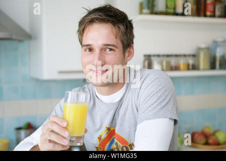 Giovane uomo con in mano un bicchiere di succo di arancia, Monaco di Baviera, Germania Foto Stock