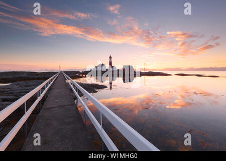 Romantico tramonto sopra il faro Tranøy Fyr sulla costa del fiordo di gilet con la parete Lofoten in background e uno stadio in primo piano Foto Stock