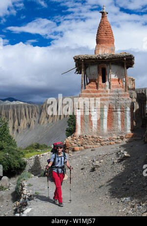 Giovane donna trekker a piedi nella parte anteriore di uno stupa buddisti, Tangge, tibetian villaggio con un Gompa buddista nel Kali Gandaki valley, la più profonda vall Foto Stock