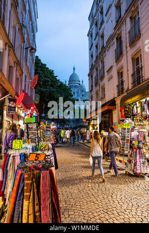 Strada con negozi di souvenir di Montmartre con la Basilica del Sacro Cuore in background, Parigi, Francia, Europa Foto Stock