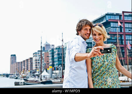 Giovane tenendo fotografia di se stessi, Magellan-Terraces, HafenCity di Amburgo, Germania Foto Stock