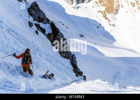 Backcountry rider in forte pendenza e con il suo cane nella Ammergauer Alpi, Baviera, Germania Foto Stock