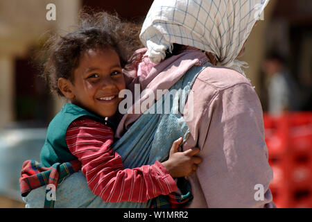 Ragazza portati dalla madre, Place el Hedim, Meknes, Marocco Foto Stock