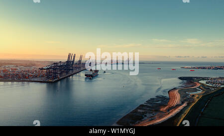 Due rimorchiatori pastore una nave portacontainer fuori dalla parete del porto di Felixstowe contenitore porta, Suffolk, Inghilterra. Foto Stock