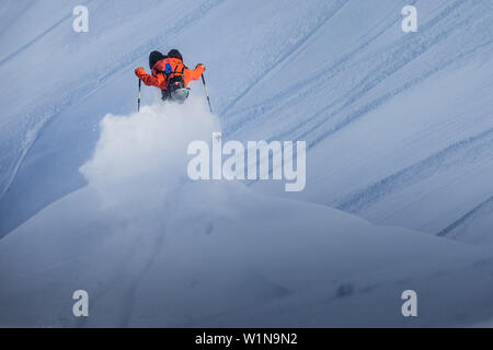 Giovane maschio sciatore facendo un backflip su una scogliera oltre i pendii, Andermatt, Uri, Svizzera Foto Stock