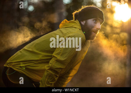 Giovani runner maschio avente una breve pausa in una foresta, Allgaeu, Baviera, Germania Foto Stock