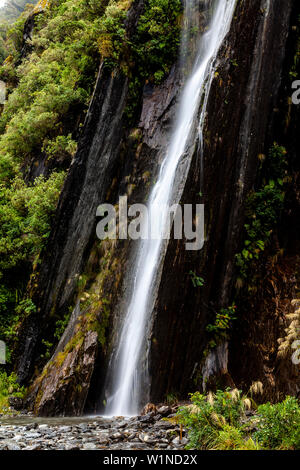 Una cascata sulla valle Walk, Ghiacciaio Franz Josef, Isola del Sud, Nuova Zelanda Foto Stock