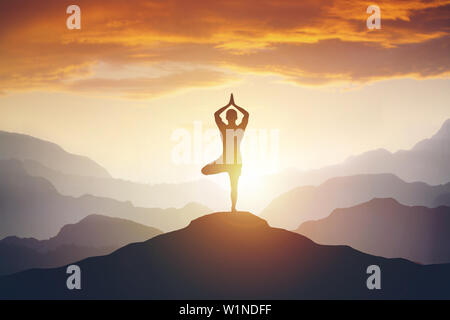 L'uomo meditando di alta montagna in background al tramonto Foto Stock