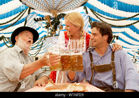 Giovane e un uomo maturo il tintinnio dei bicchieri in una tenda di birra Foto Stock