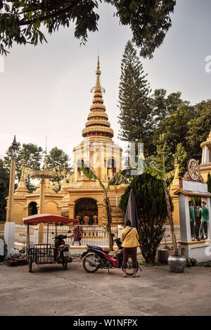 Donna tailandese con giacca gialla nella parte anteriore di una pagoda dorata nel tempio di Pai, Thailandia, Sud-est asiatico Foto Stock