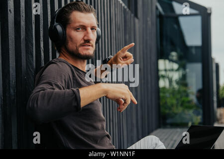 Fotografo freelance di localizzazione ho la città in montagna con il tè caldo o caffe ascolta musica in cuffia, zainetto e lavora su un notebook Foto Stock