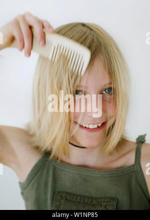 La ragazza (12 anni) pettinare capelli Foto Stock