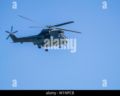 Royal Air Force elicottero, completare con enorme pistola sottolineando la porta si libra sul Hutton, Lancashire in una calda giornata estiva di fronte a un cielo blu Foto Stock